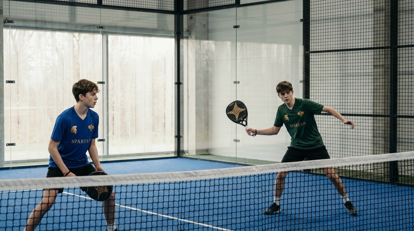 Dos adolescentes entrenando en cancha, con las camisetas verde y azul de Spartan.